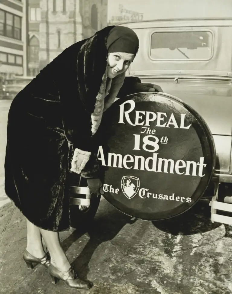 Historical photo of Miss Elizabeth Thompson standing beside a car, with a large circular sign that reads "Repeal the 18th Amendment - The Crusaders," indicating her involvement in the movement against prohibition.