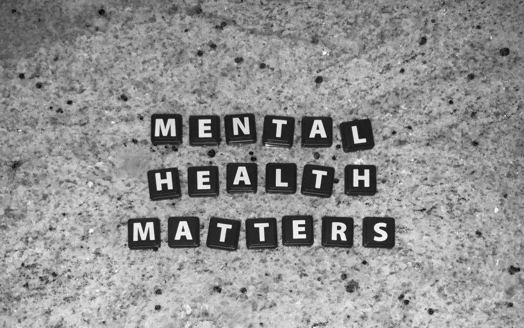 Black and white image displaying the phrase "Mental Health Matters" formed by letter tiles on a speckled stone surface.